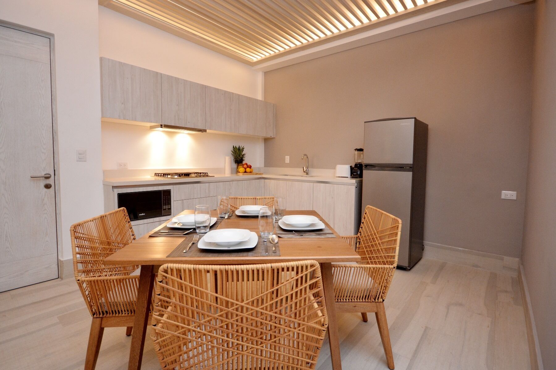 A modern kitchen with a dining table set for four, equipped with a microwave, stove, and refrigerator.