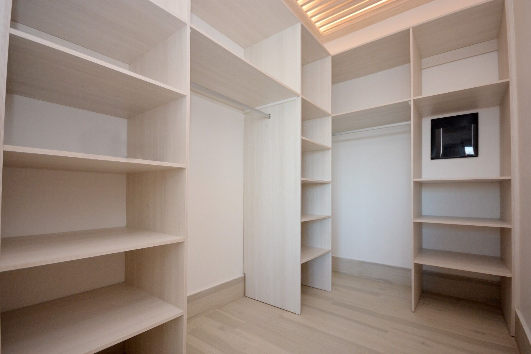 A walk-in closet with multiple shelves and a sliding door.