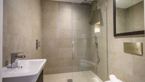 Une salle de bain moderne avec une douche à parois de verre, un lavabo blanc et un grand miroir.
