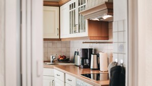 A kitchen with white cabinets, a wooden countertop, a coffee maker, and a kettle.