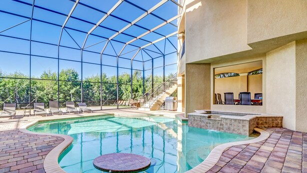 An indoor swimming pool with a glass ceiling, lounge chairs, and a barbecue area. - Southern Charm Close To Beach (Marco Island)