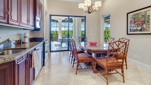 A modern kitchen with dark wood cabinets, a granite countertop, and a built-in oven. - Southern Charm Close To Beach (Marco Island)