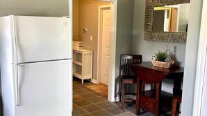 Una cocina con un refrigerador blanco, una mesa de comedor con sillas y un espejo en la pared.