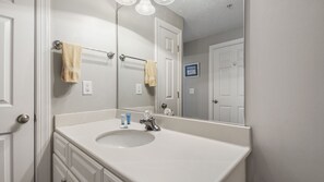 A bathroom with a white sink, a mirror, and a towel rack. - Emerald Isle 2209 -Beachfront condo! Beach chairs included! Assigned parking! (Panama City Beach)