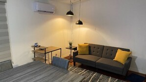 Un salon moderne avec un canapé gris, une table à manger en bois et une petite table d’appoint sur laquelle est posée une plante.