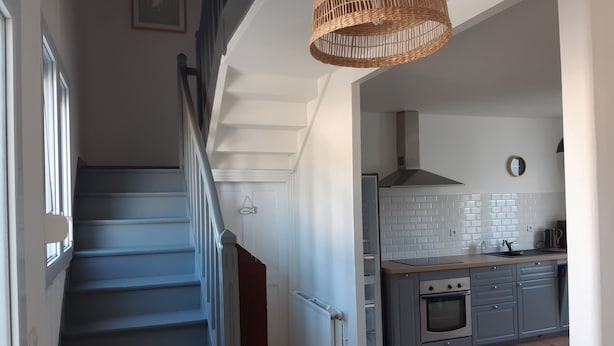 Eine Treppe führt zu einer Küche mit modernem Design, inklusive eingebautem Ofen und einer Pendelleuchte.