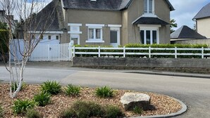 Ein zweistöckiges Haus mit weißem Zaun, einer Auffahrt und einem Steinelement im Vorgarten.