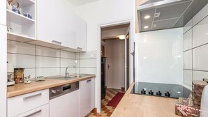A compact kitchen with white cabinets, a wooden countertop, and a red and beige checkered floor.