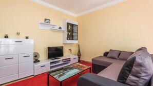 A living room with a sofa, a TV, a white cabinet, and a red carpet.