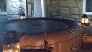 A hot tub with a stone wall backdrop, a wooden deck, and a lantern on the side. - Ruby Charm Houses 9 116352/AL (Porto)