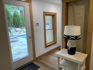 Ein Zimmer mit einer Tür zu einem Poolbereich, einem Fenster mit einem Sicherheitshinweis und einem Tisch mit einer Lampe.