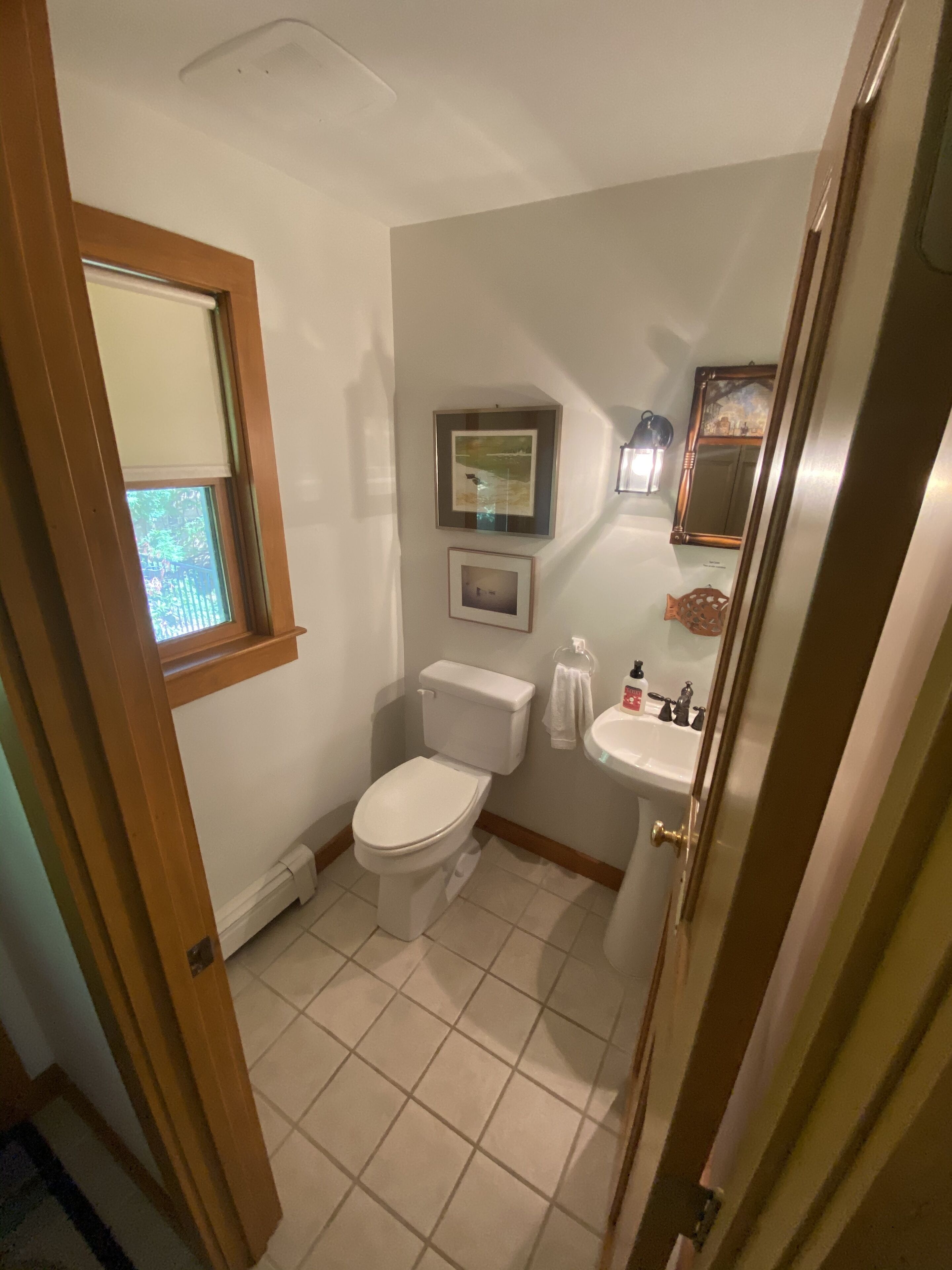 A bathroom with a toilet, sink, and a window.