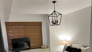 A bedroom with a bed, bedside lamps, a TV, a wooden headboard, and a bench. - Beautiful ski in-ski out condo at Okemo Mountain (Ludlow)