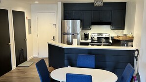 A modern kitchen with dark cabinets, a stainless steel refrigerator, and a white countertop. - Beautiful ski in-ski out condo at Okemo Mountain (Ludlow)