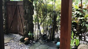 A garden with a stone wall, a wooden gate, and a tiled walkway. - Tranquil apartment near beach front  (Playa Zancudo)