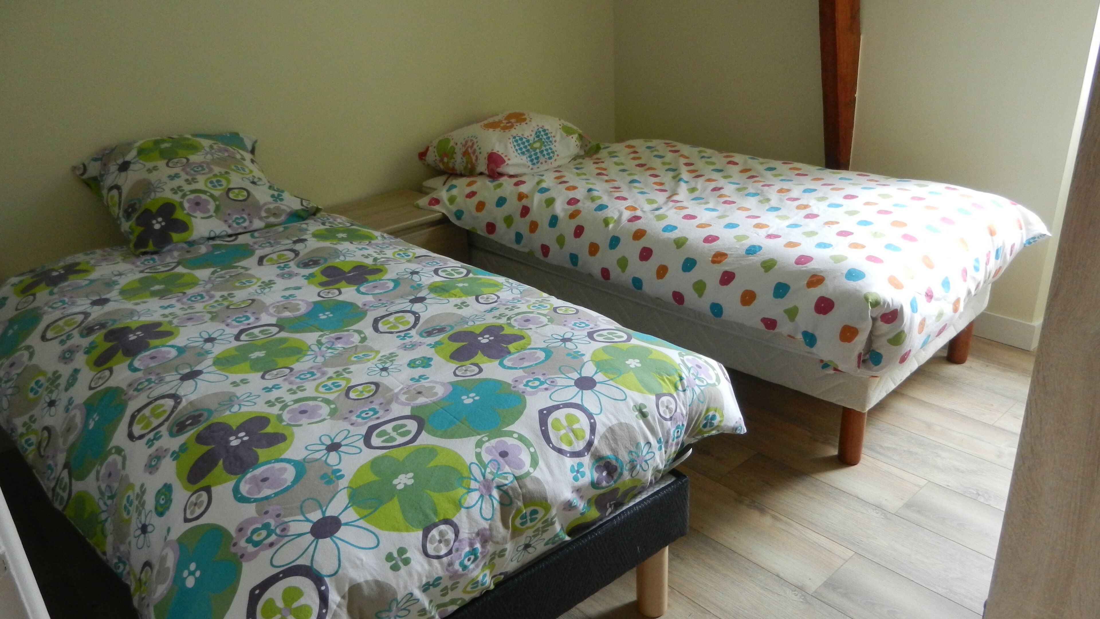 A room with two single beds, each with a floral-patterned bedspread.