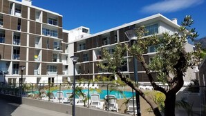 A multi-story hotel with balconies, a swimming pool, and outdoor seating.