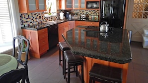 Una cocina con armarios de madera, un refrigerador negro, un microondas y un salpicadero de azulejos.