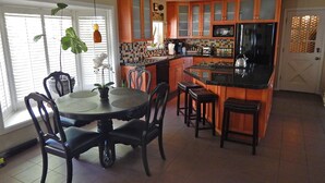 Una cocina con una isla central, armarios de madera y un comedor con sillas y una mesa.