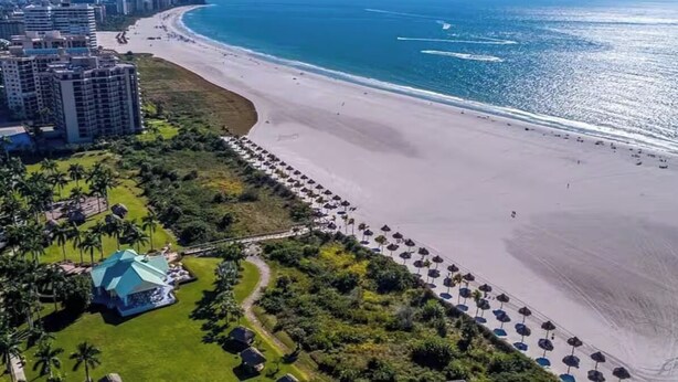An aerial view of a coastal resort with beachfront properties, a sandy beach, and a clear view of the ocean. - 5 min walk to the beach, perfect pool, bbq, spa, beautiful home (Marco Island)