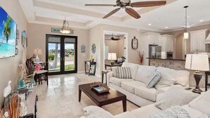 A spacious living room with a ceiling fan, a sofa, a coffee table, and a dining area with chairs. - 5 min walk to the beach, perfect pool, bbq, spa, beautiful home (Marco Island)