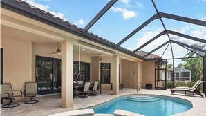 A swimming pool with a glass ceiling, lounge chairs, and a patio area. - 5 min walk to the beach, perfect pool, bbq, spa, beautiful home (Marco Island)