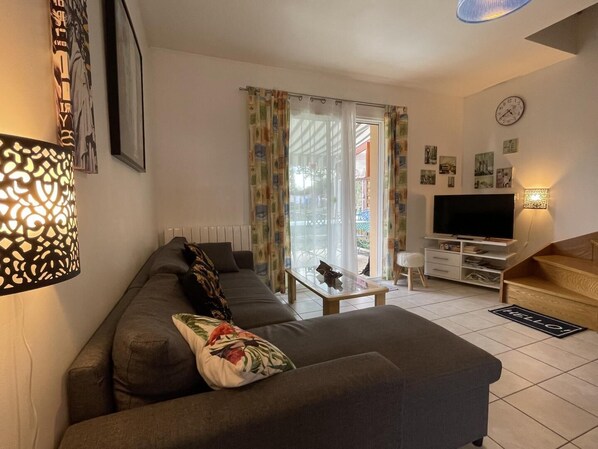 A living room with a sofa, a coffee table, a TV, and a staircase.