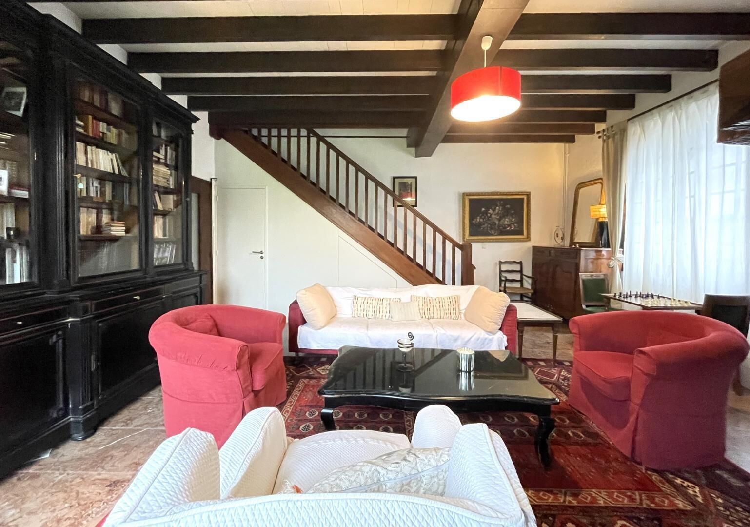 Un salon chaleureux avec un escalier, une bibliothèque, un ensemble de canapés et une table de baby-foot.