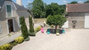 A courtyard with a building, a tree, and outdoor seating. - Chez Laborde - Riupeyrous (RIUPEYROUS)