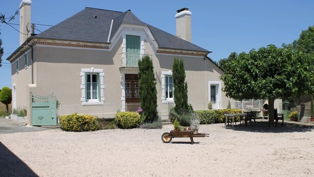 A two-story house with a gravel driveway, a wooden cart, and a small outdoor seating area. - Chez Laborde - Riupeyrous (RIUPEYROUS)