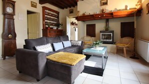 A cozy living room with a dark grey sofa, a wooden coffee table, and a fireplace. - Chez Laborde - Riupeyrous (RIUPEYROUS)