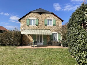 A stone house with green shutters, a covered patio, and a well-maintained lawn. - Chez Evon - Jurancon (JURANCON)