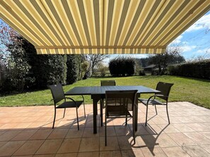 An outdoor patio with a table and chairs under a striped awning. - Chez Evon - Jurancon (JURANCON)