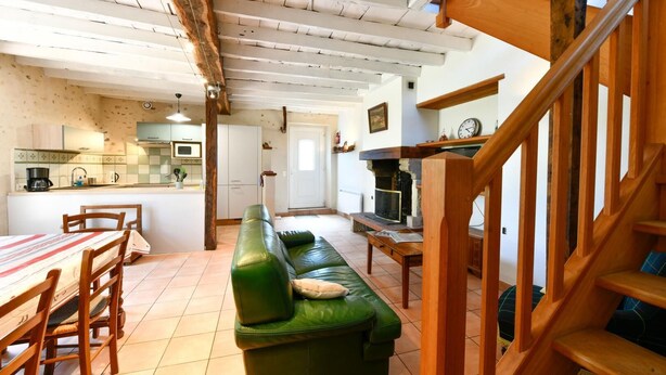 A cozy living room with a green sofa, wooden dining table, and a staircase. - Chez Evon - Jurancon (JURANCON)