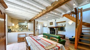 A spacious living area with a dining table, green sofa, and a wooden staircase. - Chez Evon - Jurancon (JURANCON)
