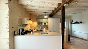 A modern kitchen with a central island, white cabinetry, and a microwave. - Chez Evon - Jurancon (JURANCON)