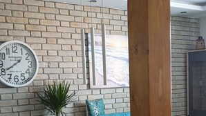 Une cuisine moderne avec un îlot central en bois, une horloge et un mur en briques.