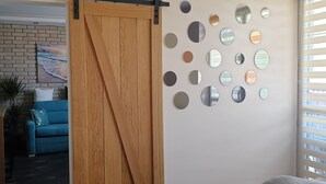 Une pièce avec un canapé bleu, une porte coulissante en bois et un mur décoré de miroirs ronds.