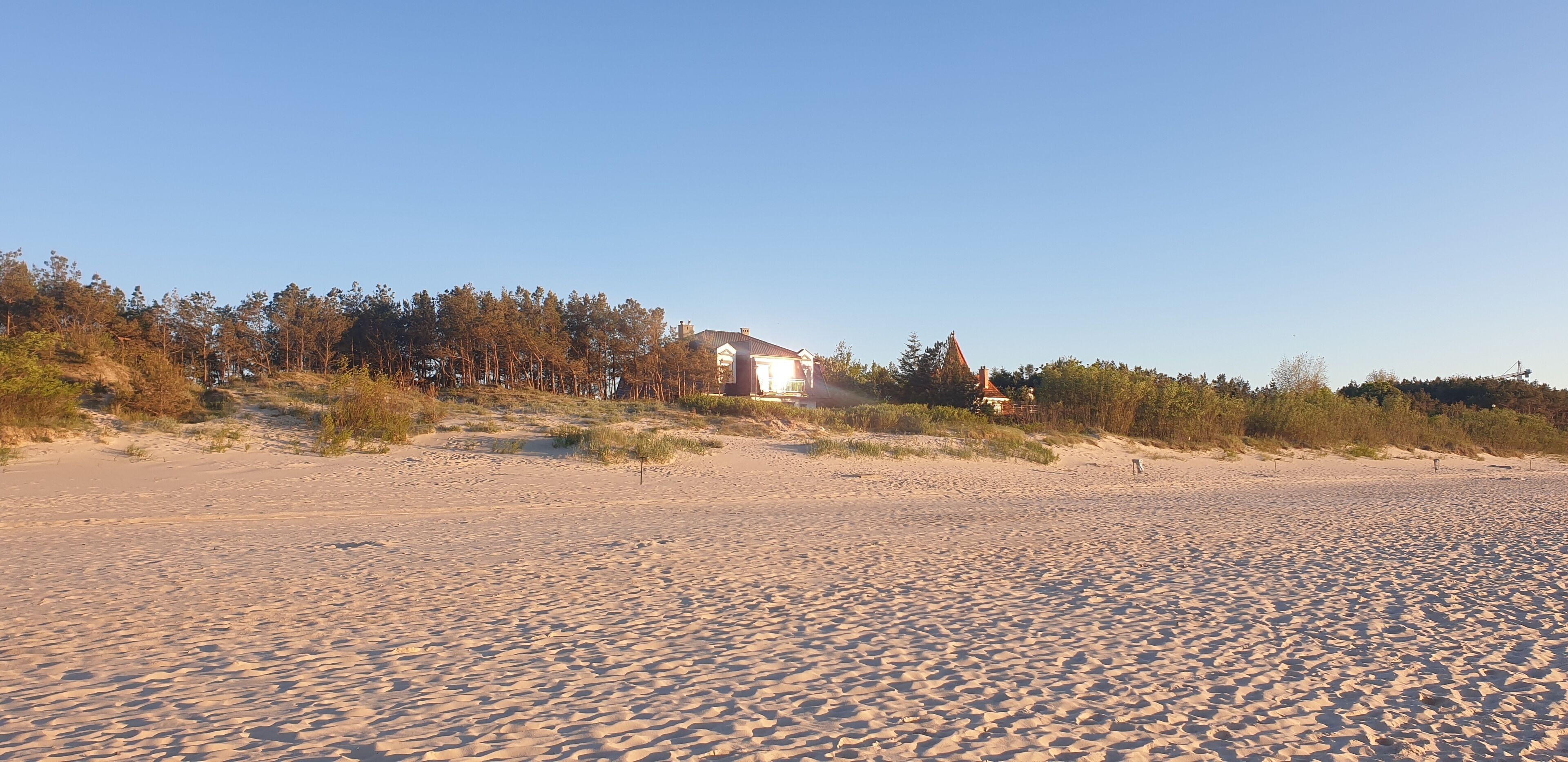 A sandy beach with a house in the background.