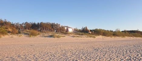 A sandy beach with a house in the background.