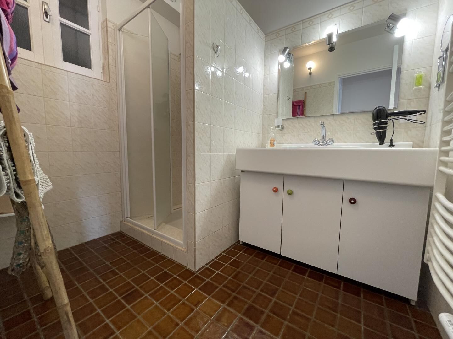 A bathroom with a shower, a sink with a mirror, and a towel rack.