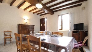 Un coin repas avec une table en bois, des chaises et un téléviseur posé sur un meuble.