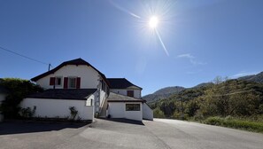A two-story house with a sloped roof, a garage, and a driveway leading to a paved road. - Iagonia - Lacarry - Gîte (LACARRY)