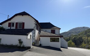 A two-story house with a garage, a staircase, and a view of a forested hill. - Iagonia - Lacarry - Gîte (LACARRY)