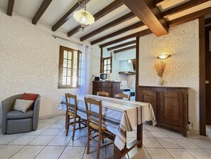 Un comedor con mesa, sillas, un sofá y una cocina al fondo.