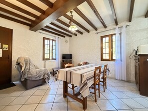 Un espace repas comprenant une table, des chaises, un canapé, un téléviseur et un coin cuisine avec des placards.