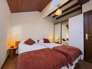 Una cama doble con dos almohadas, un cabecero de madera, una mesita de noche con lámpara y un espejo en la pared.