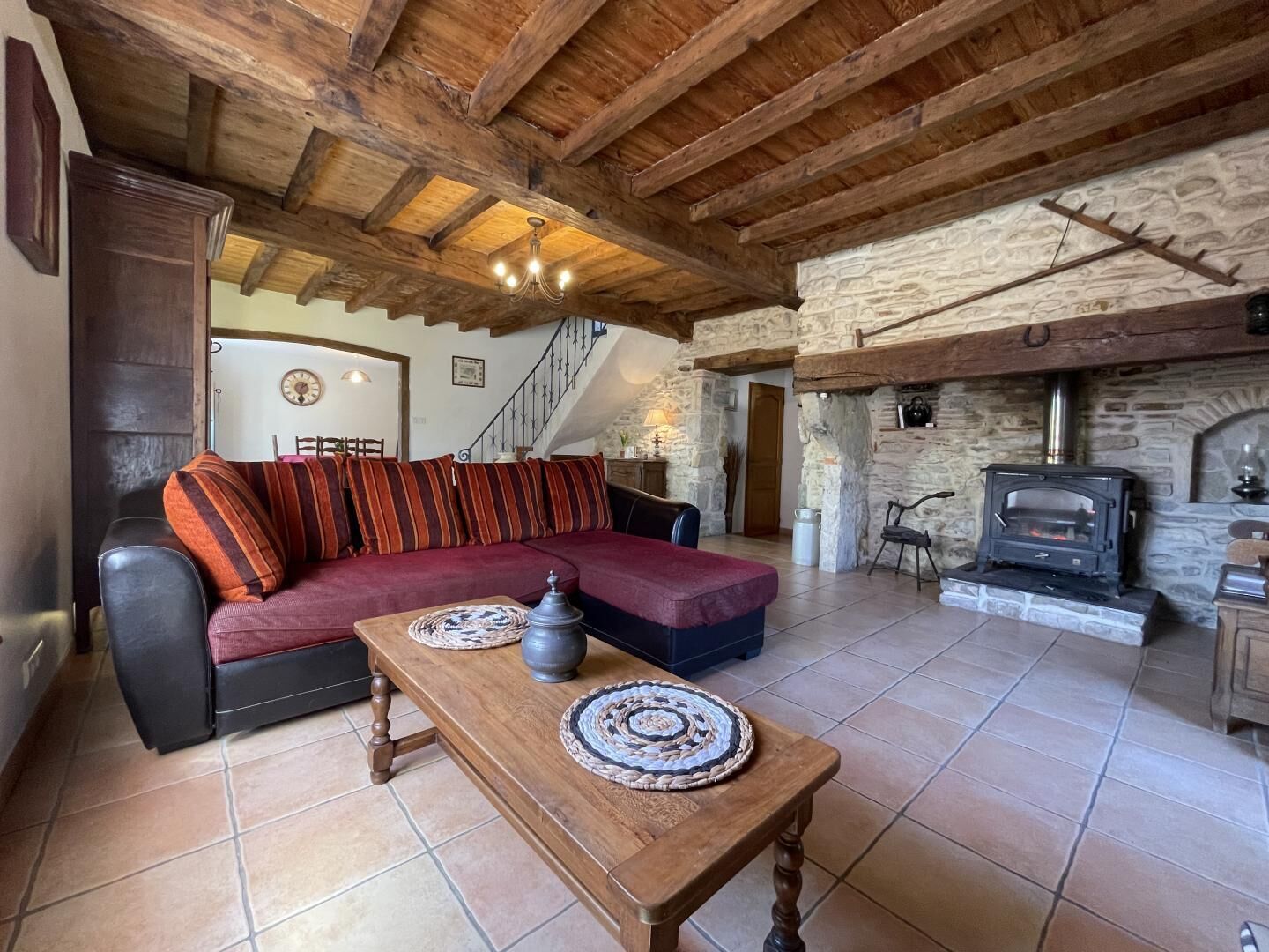A cozy living room with a stone fireplace, wooden beams, a sofa, and a coffee table.