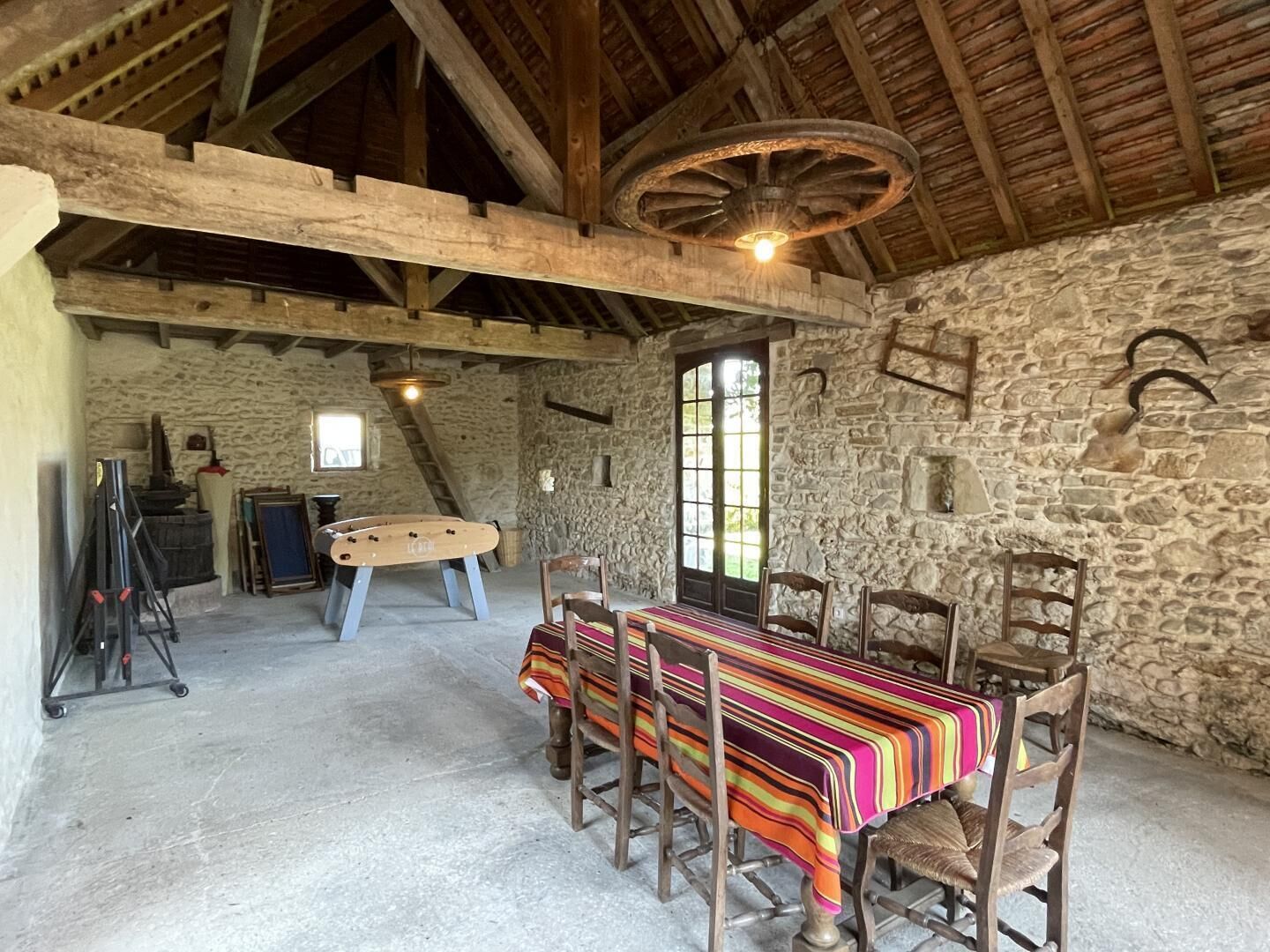 Un'accogliente sala da pranzo in stile rustico, con tavolo e sedie in legno, pareti in pietra e soffitto spiovente con travi a vista.