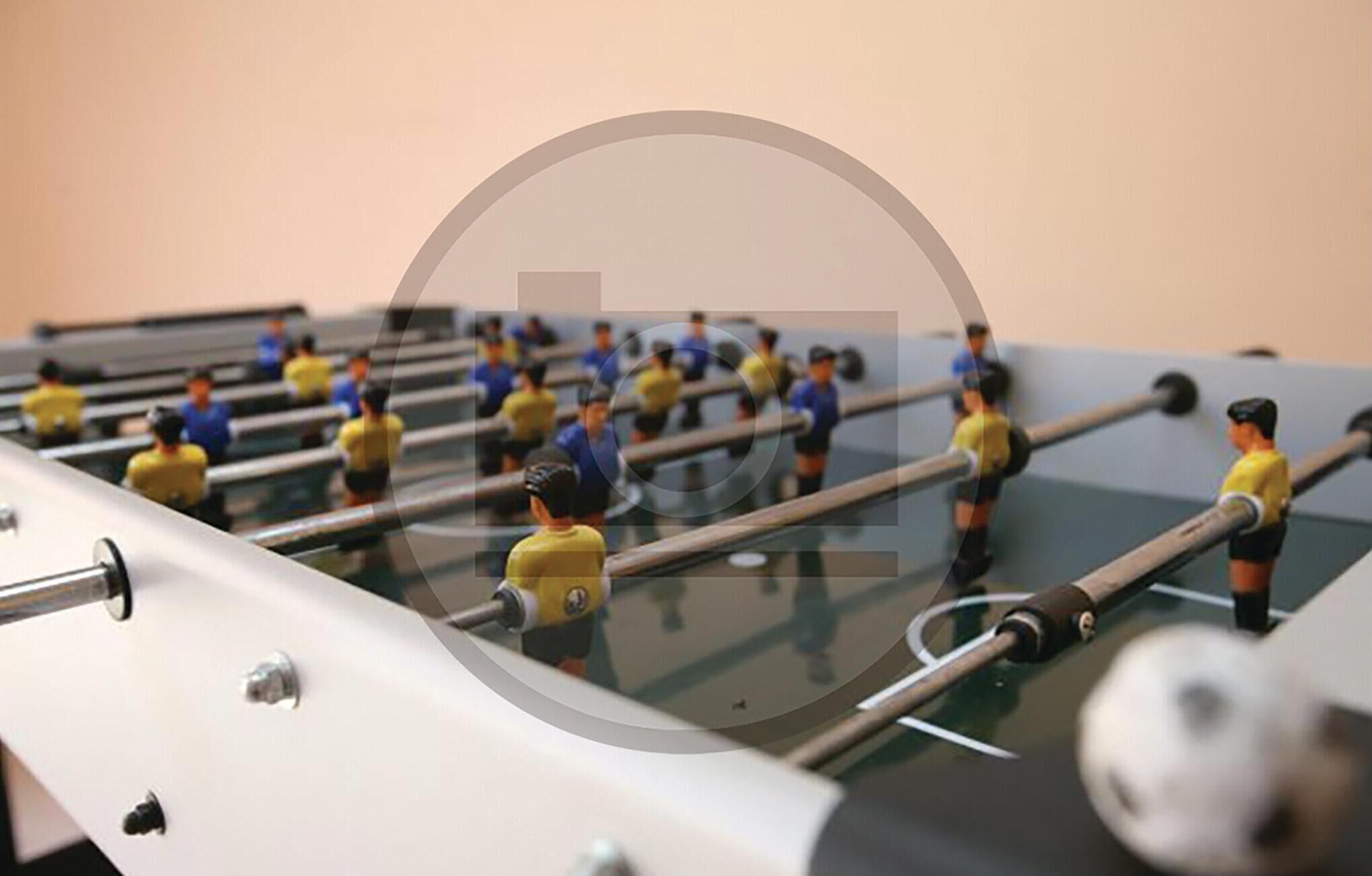 A foosball table with miniature figures in yellow and blue uniforms.